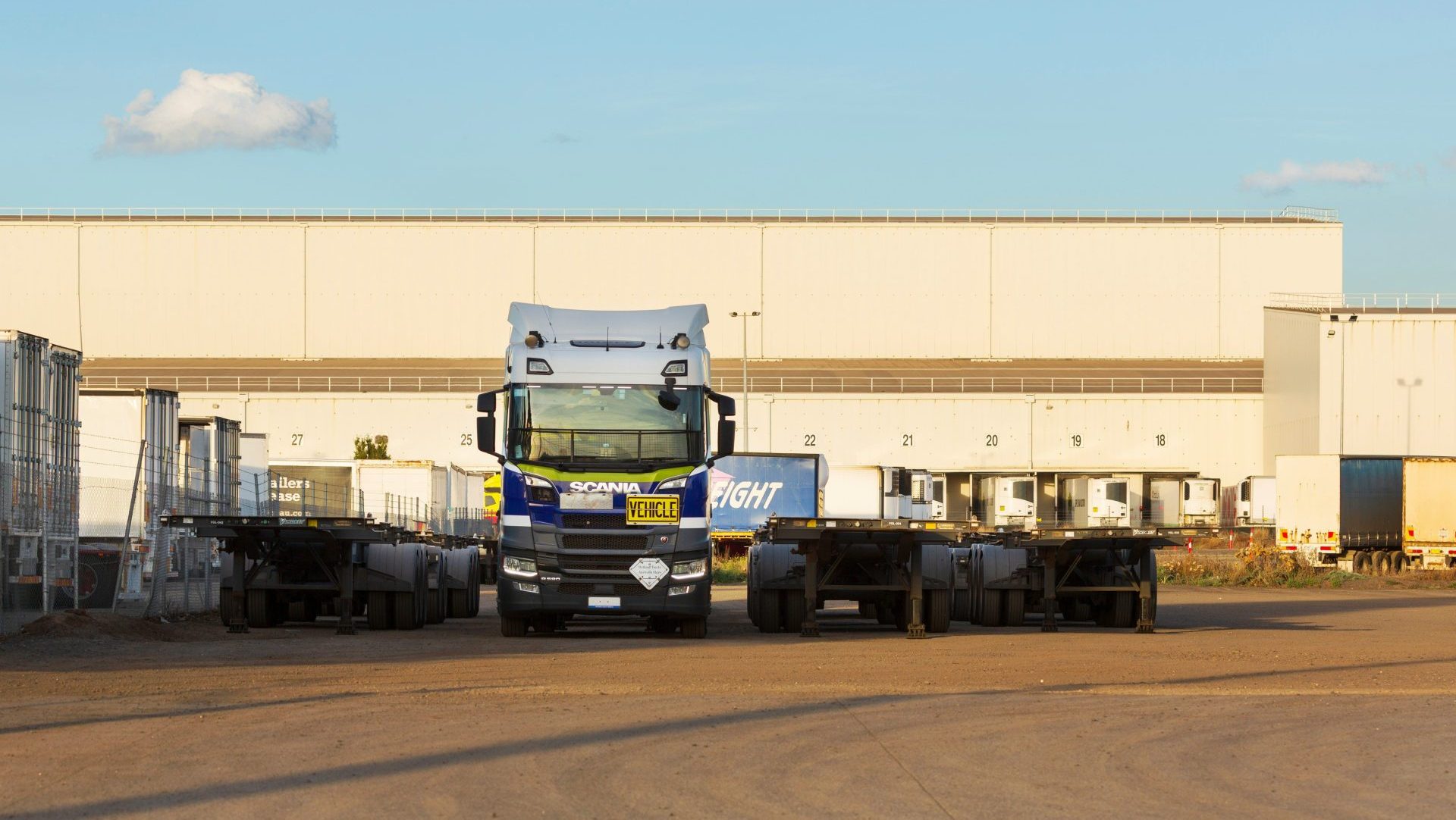 Truck and trailers parked in front of a warehouse.